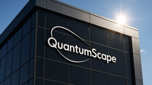 Close-up of QuantumScape signage on a dark glass office building facade with bright sunlight and blue sky