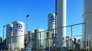 Outdoor industrial site with white Air Liquide tanks, tall columns, and metal pipework under a clear blue sky